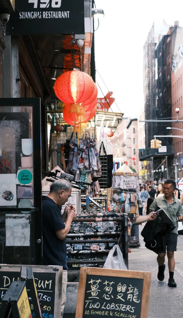 A red lantern hangs over a crowded shop-lined street.