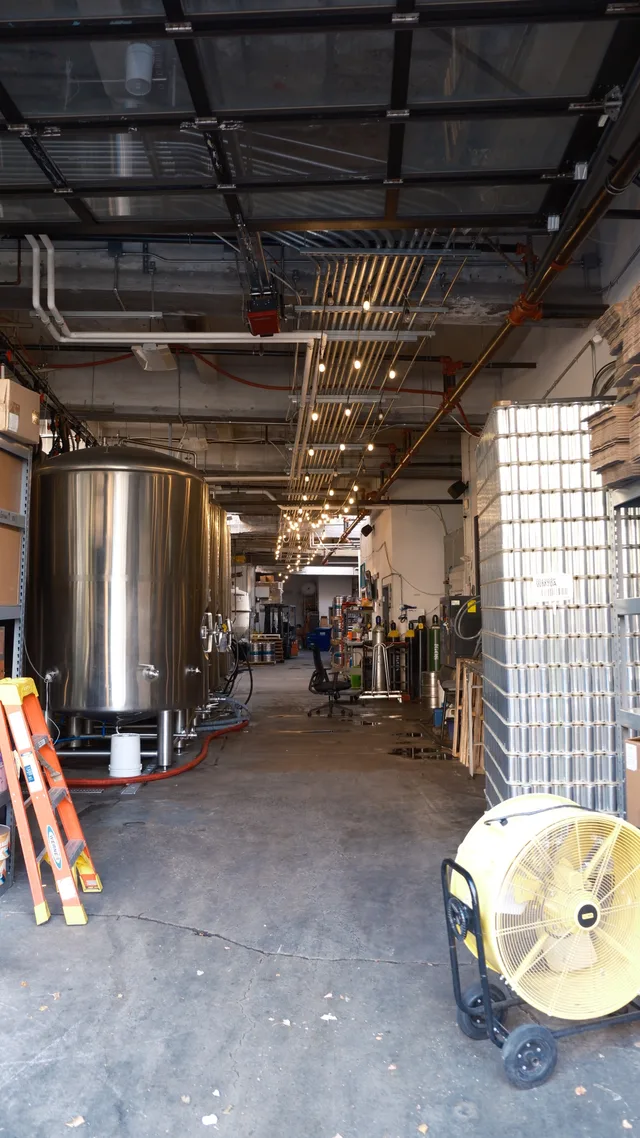 A utility corridor reveals tanks, ducts, cables and a floor fan.