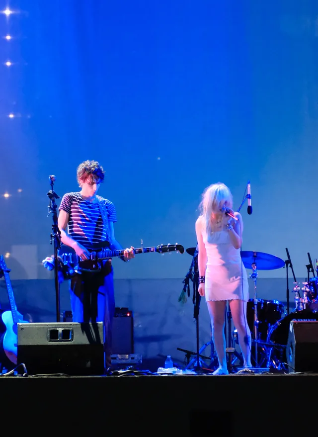 A guitarist and singer occupy separate pools of blue stage light.
