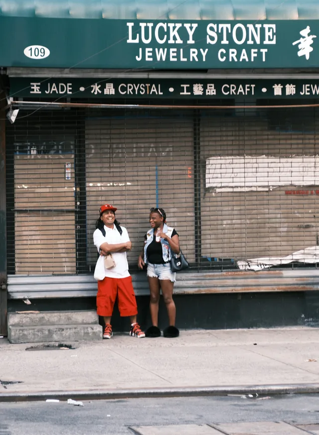 Two people stand beneath the Lucky Stone sign outside a closed shutter.