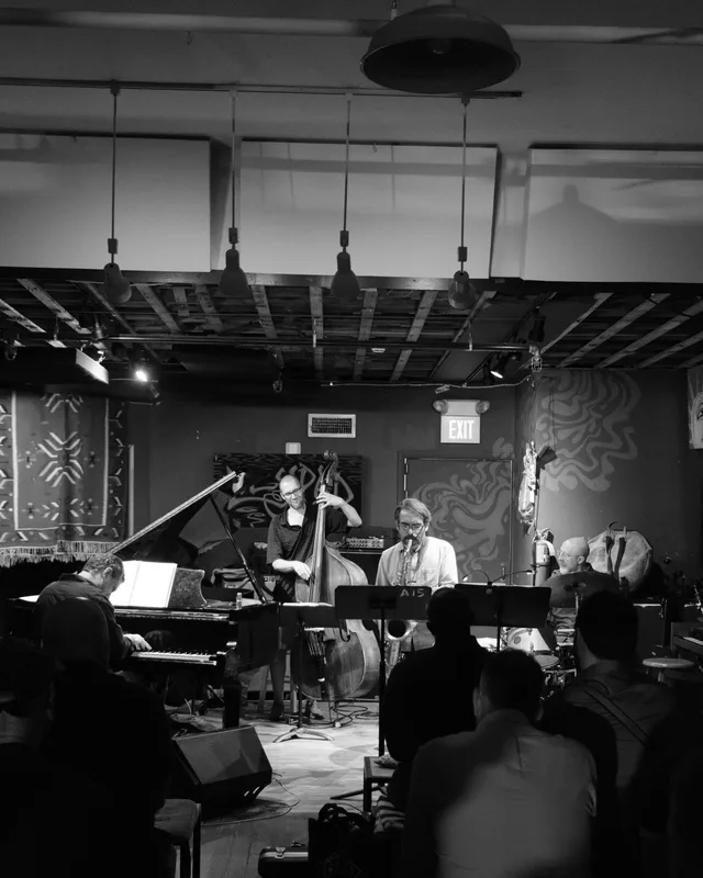 A small ensemble performs beyond dark audience silhouettes.