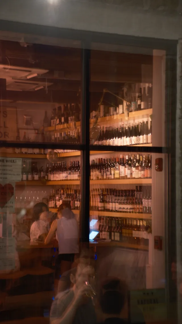 A warm interior is seen through a divided window with overlapping reflections.